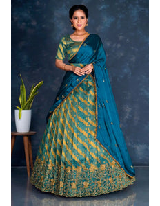 Woman wearing a traditional teal and gold lehenga choli with dupatta