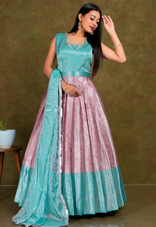 Woman wearing a traditional outfit with a teal top and pink gown with dupatta