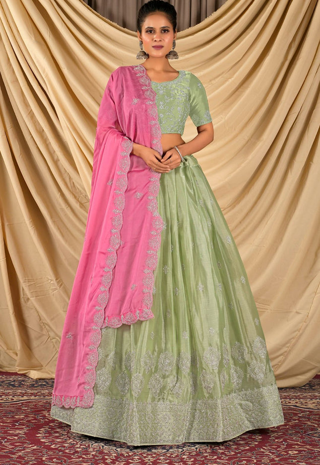 Woman wearing a green and pink lehenga choli with dupatta