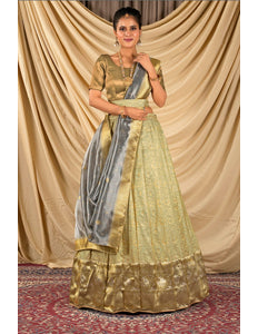Woman wearing a traditional gold and green lehenga choli with dupatta