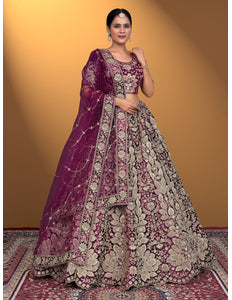 Woman wearing a traditional embroidered outfit with a purple dupatta