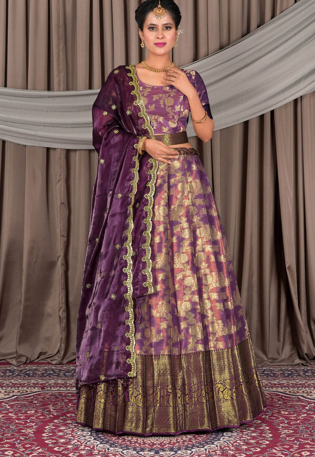 Woman wearing a traditional purple and gold outfit with a matching dupatta