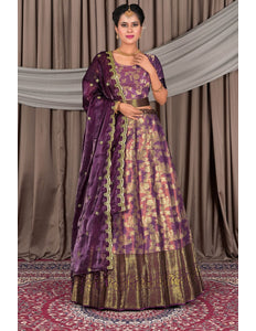 Woman wearing a traditional purple and gold outfit with a matching dupatta