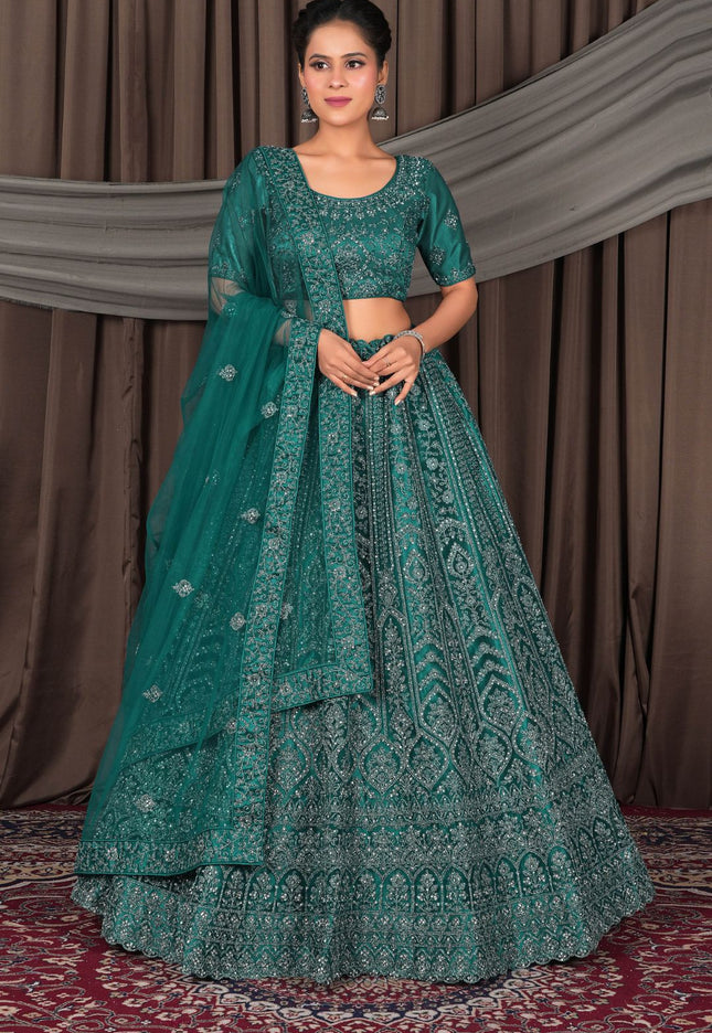 Woman wearing a traditional teal embroidered outfit with a matching dupatta