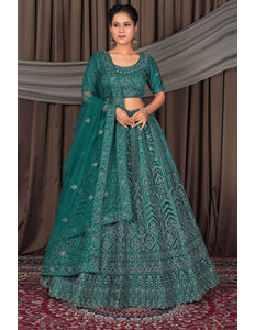 Woman wearing a traditional teal embroidered outfit with a matching dupatta