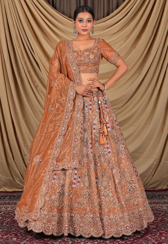 Woman wearing a traditional orange and gold embroidered lehenga choli with dupatta
