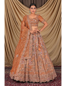 Woman wearing a traditional orange and gold embroidered lehenga choli with dupatta