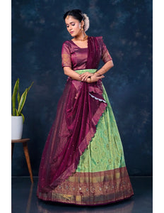 Woman wearing a traditional maroon and green lehenga choli with dupatta