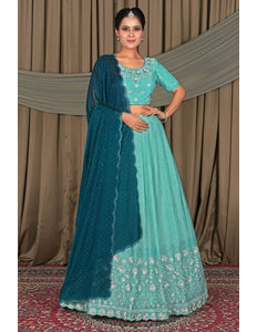 Woman wearing a traditional outfit with a teal dupatta and light blue dress