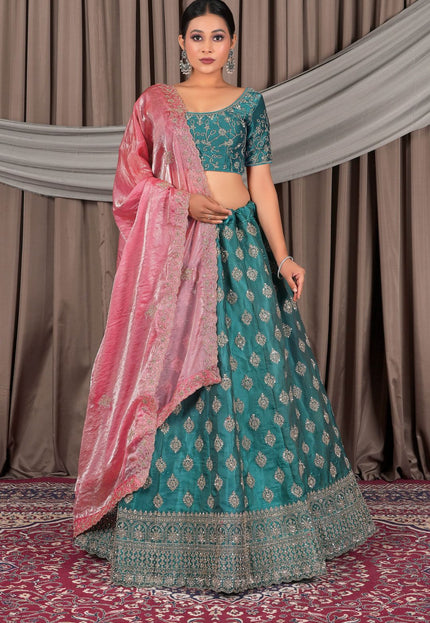 Woman in a teal traditional outfit with pink dupatta