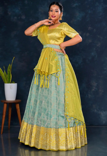 Woman wearing a traditional outfit with a yellow and sea green lehenga choli