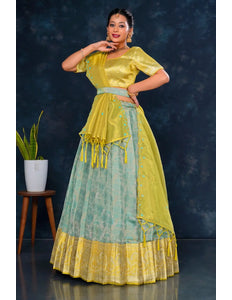 Woman wearing a traditional outfit with a yellow and sea green lehenga choli