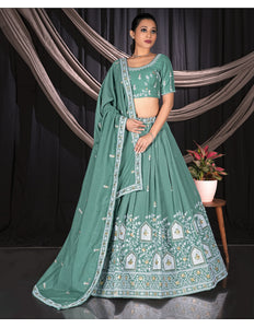 Woman wearing a green embroidered traditional outfit with a matching dupatta