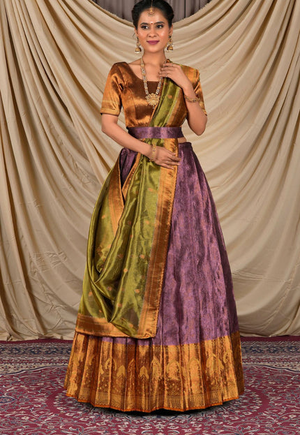 Woman wearing a traditional outfit with a gold, green, and purple lehenga choli with dupatta