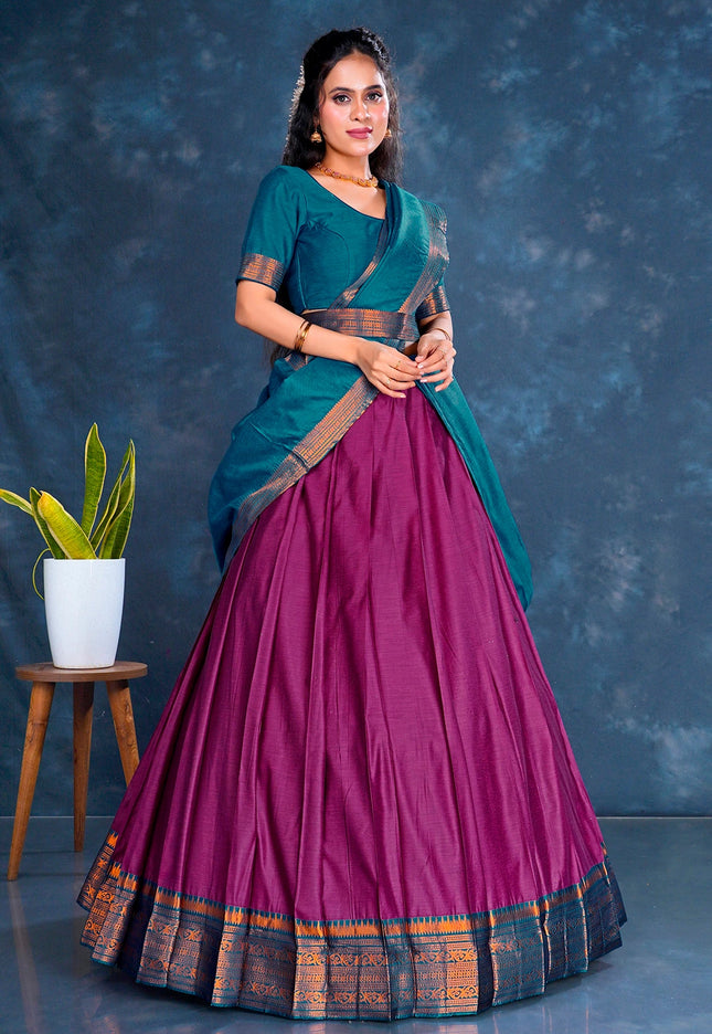 Woman wearing a traditional outfit with a blue blouse and pink saree against a dark blue background.