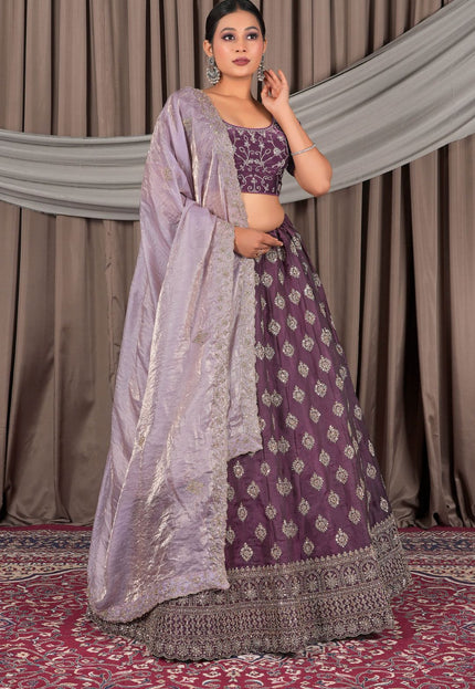 Woman wearing a traditional purple and gray lehenga with a matching dupatta