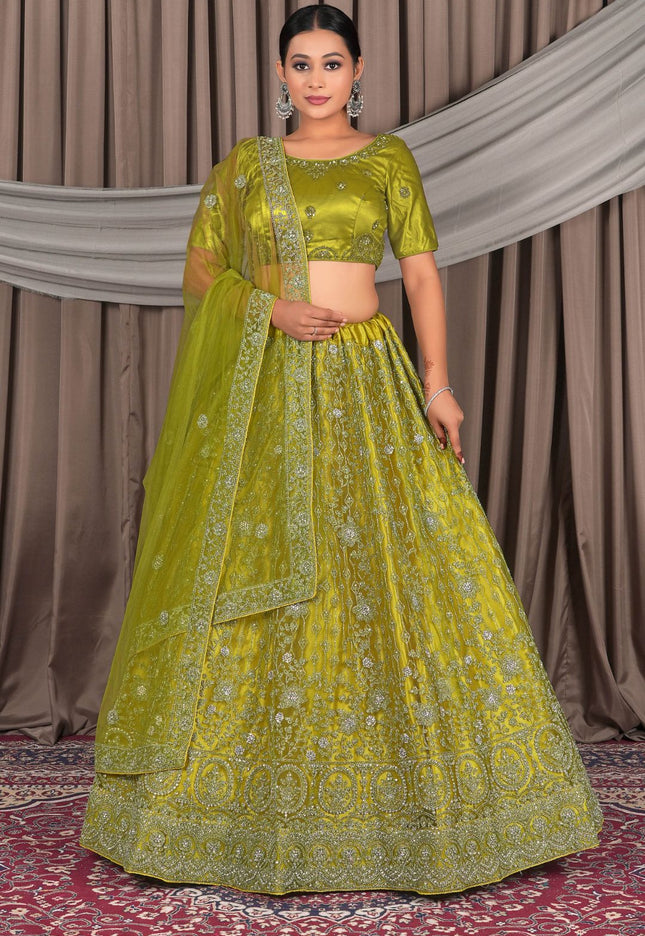 Woman wearing a green embroidered traditional outfit with a matching dupatta