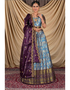 Woman wearing a traditional outfit with a purple and blue lehenga choli with dupatta